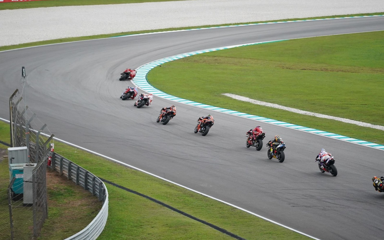 Motorcycle racers lean through a curve in a pack during a track race